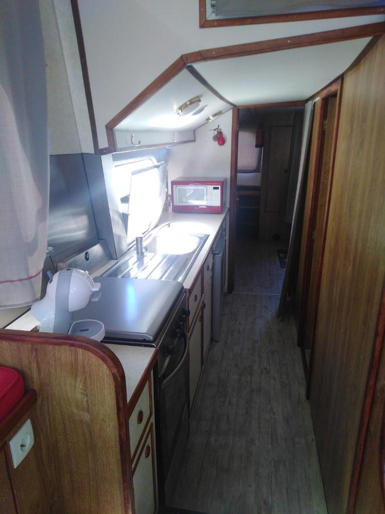 une petite cuisine avec un évier et une cuisinière dans l'établissement BATEAU - Jolie pénichette sur région touristique., à Bellegarde