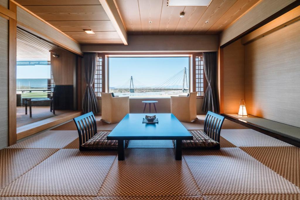 une salle à manger avec une table, des chaises et un pont dans l'établissement Tokachigawa Onsen Daiichi Hotel, à Otofuke