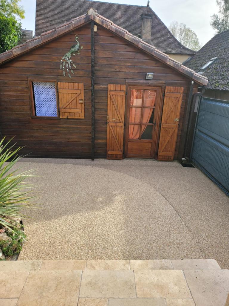 un garage avec deux portes en bois et une allée. dans l'établissement Au petit Chalet, à Gigouzac