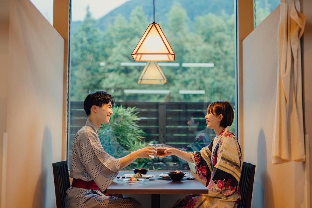 un homme et une femme assis à une table tenant la main dans l'établissement SEKIYA RESORT Terrace Midoubaru, à Beppu