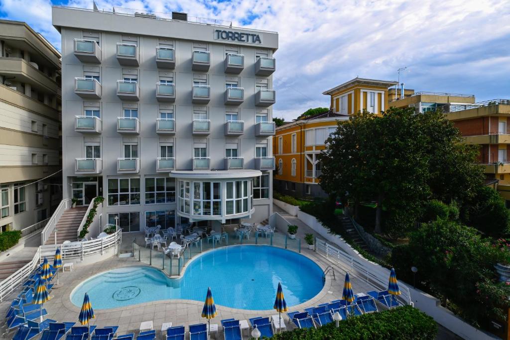un hôtel avec une piscine devant un bâtiment dans l'établissement Hotel Torretta, à Cattolica
