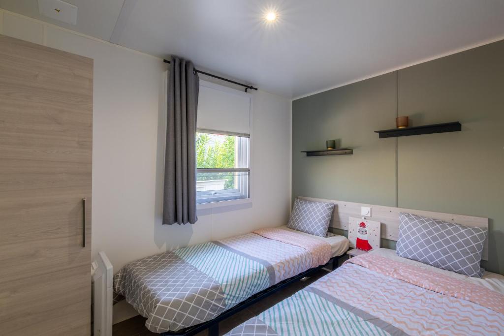 deux lits dans une chambre avec une fenêtre dans l'établissement Mobil home Queen Margaret, à Fréjus