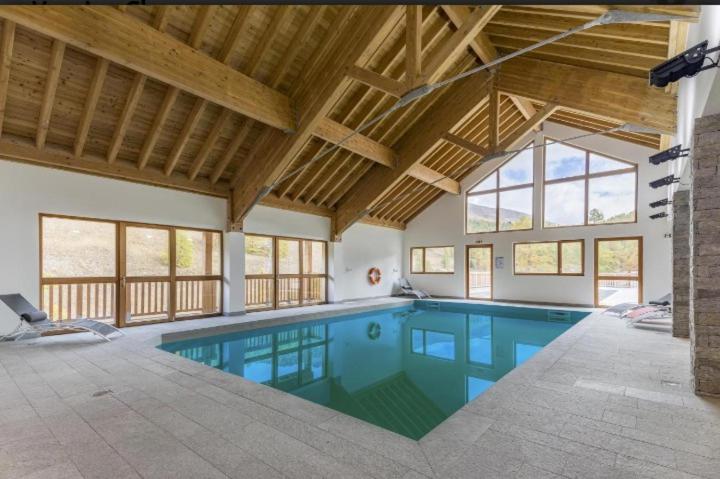 une grande piscine dans une maison avec un plafond dans l'établissement Appt Le Hameau Des Rennes 4 étoiles Pieds des pistes Piscine Intérieure Extérieure, à Vars 25 autres photos