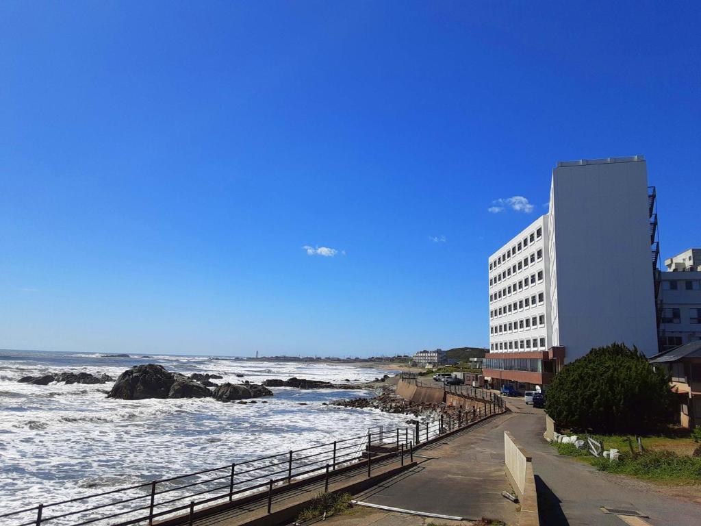 un bâtiment sur la plage avec l'océan et un bâtiment dans l'établissement 銚子グランドホテル, à Choshi
