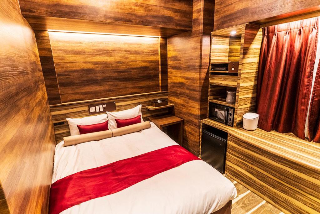 une chambre avec un lit dans une pièce aux murs en bois dans l'établissement Petit Bali Forest Shinjuku Sanchōme, à Tokyo