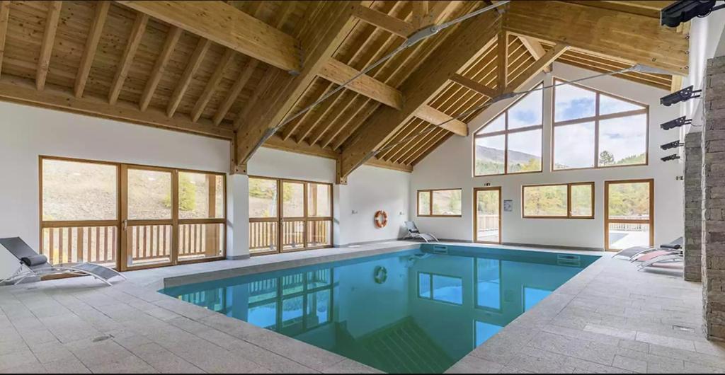 - une piscine dans une maison avec fenêtres dans l'établissement Appt Le Hameau Des Rennes 4 étoiles Pieds des pistes Piscine Intérieure Extérieure, à Vars