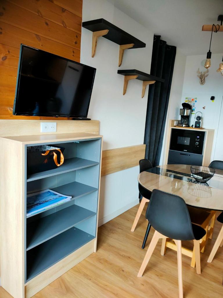 - un salon avec une table et une télévision sur une armoire dans l'établissement Risoul Appartement 2 chambres Piscine Balcons de Sirius, à Risoul