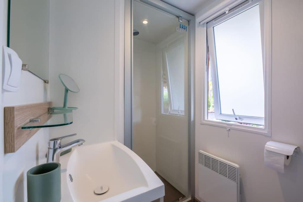 une salle de bain blanche avec un lavabo et une fenêtre dans l'établissement Little John, à Fréjus