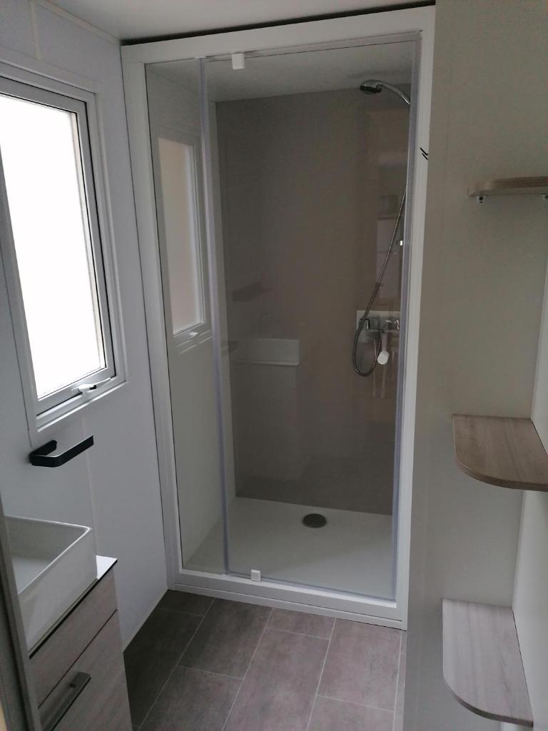 une douche avec une porte vitrée dans une salle de bain dans l'établissement Mobil Home camping 4 étoiles, à Gastes