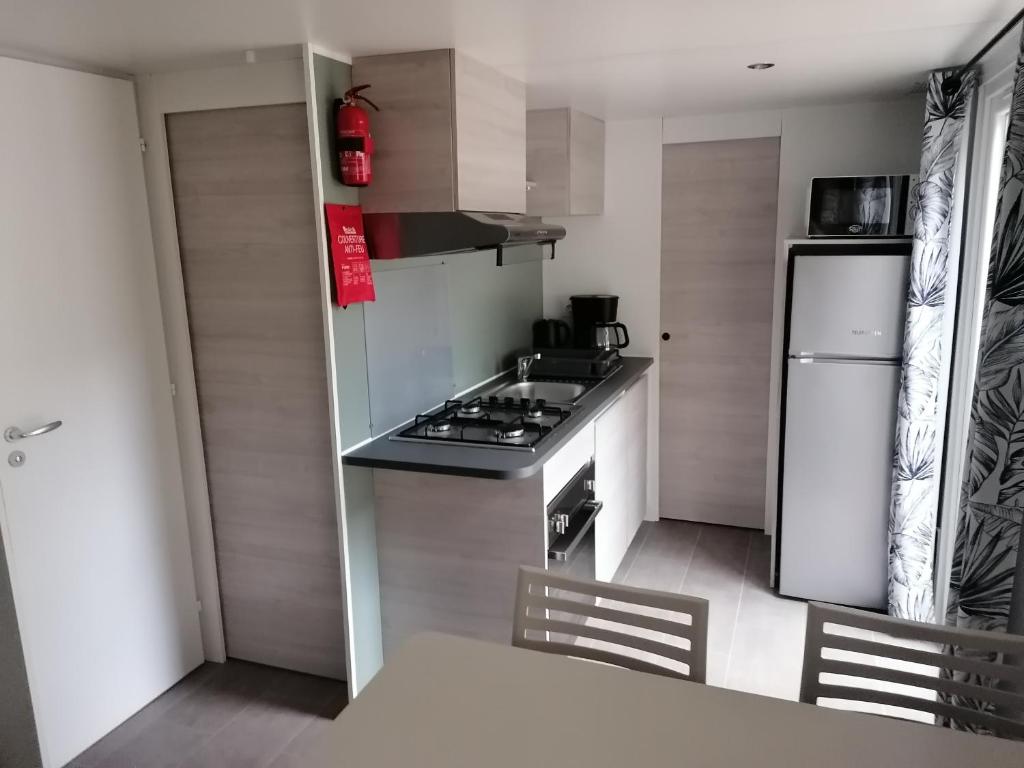 Il comprend une petite cuisine équipée d'une cuisinière et d'un réfrigérateur. dans l'établissement Mobil Home camping 4 étoiles, à Gastes 5 autres photos