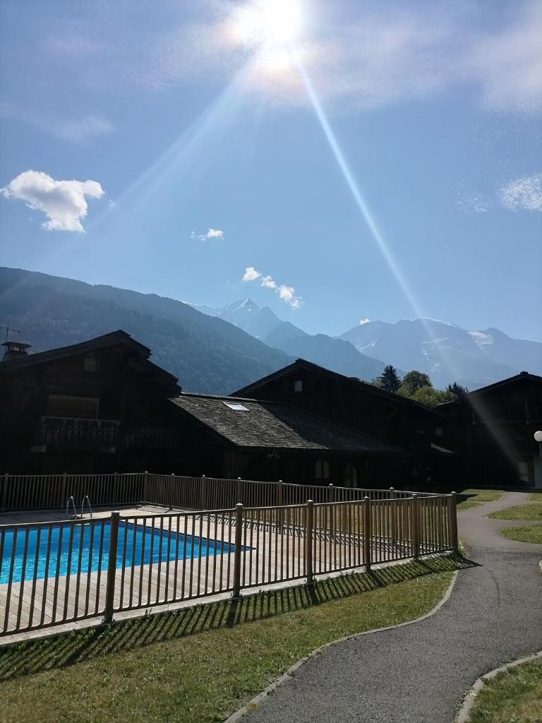 une clôture à côté d'une piscine avec des montagnes en arrière-plan dans l'établissement Appartement aux pieds des pistes / piscine, à Saint-Gervais-les-Bains