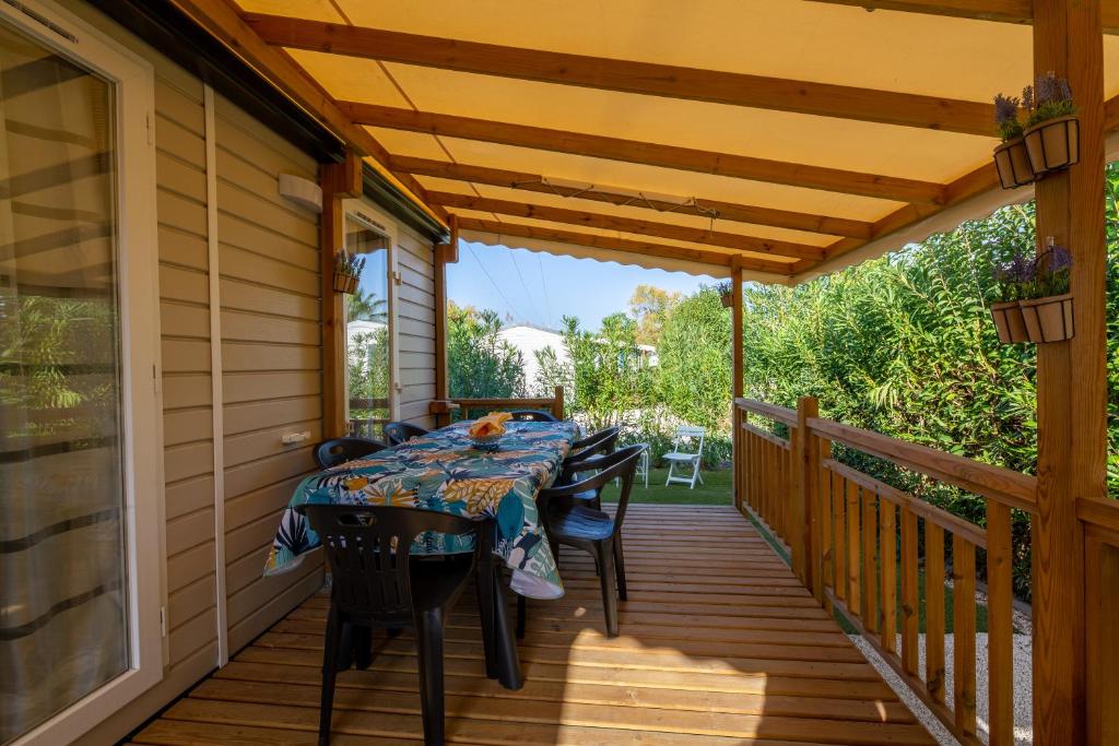 une terrasse en bois avec une table et des chaises dessus dans l'établissement Mobil home Queen Margaret, à Fréjus