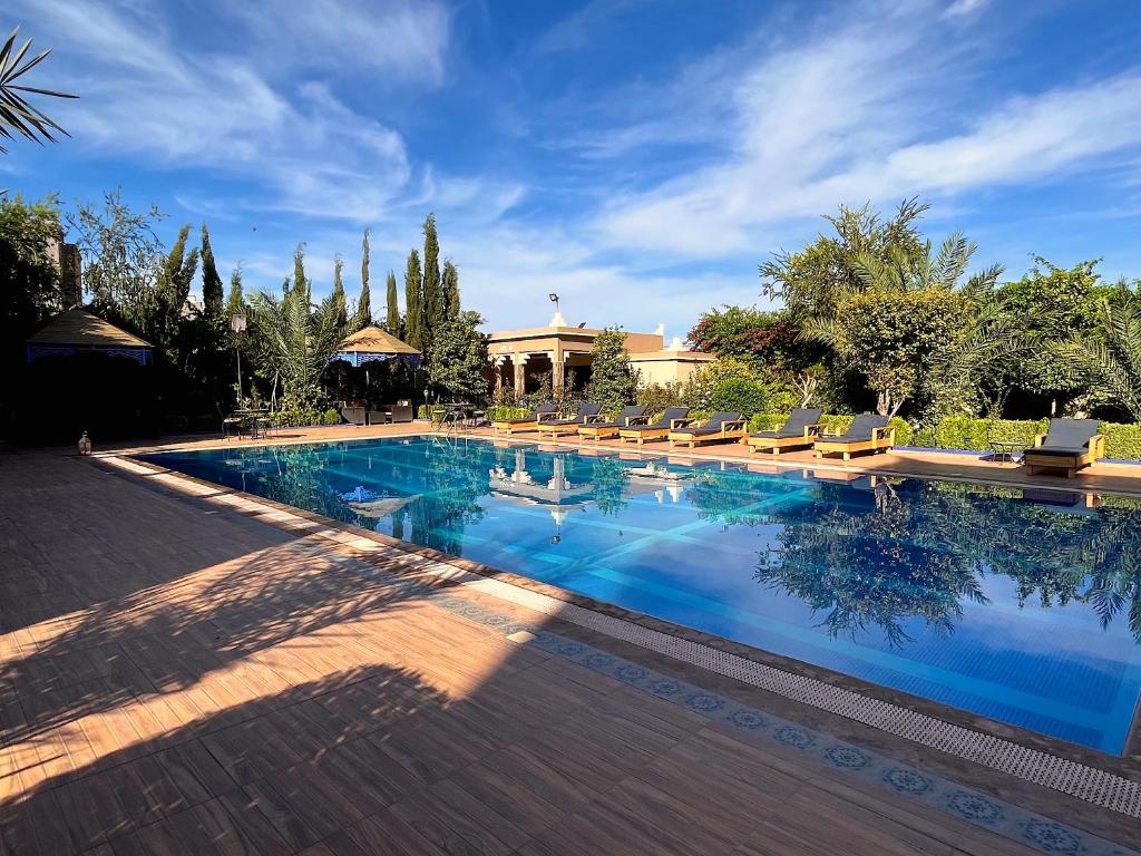 une grande piscine avec des chaises et une maison dans l'établissement Ksar Ben Youssef, à Ouarzazate