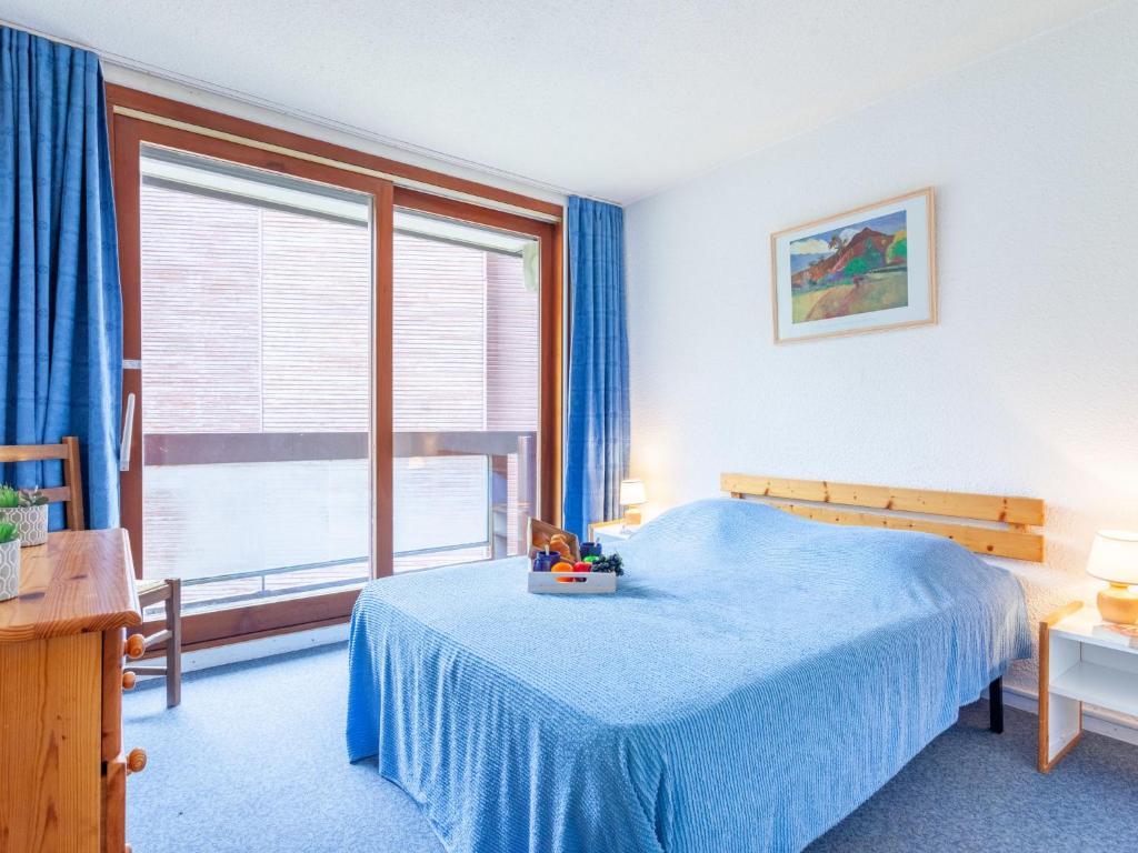 une chambre avec un lit bleu et une grande fenêtre dans l'établissement Apartment Lunik Orion-23 by Interhome, au Corbier