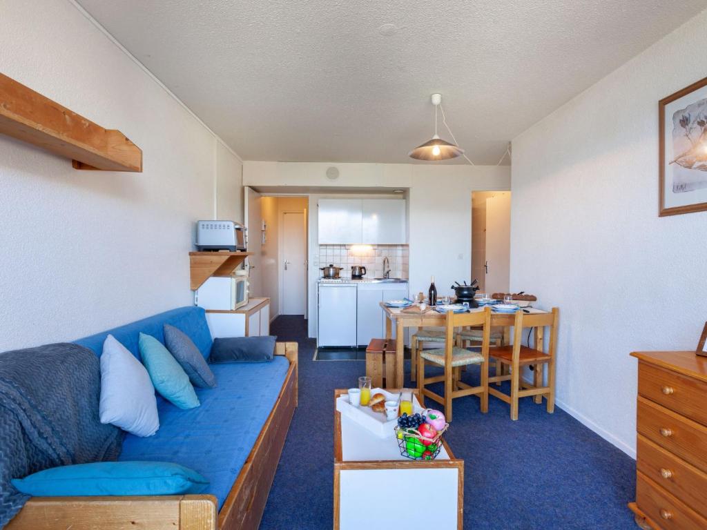 un salon avec un canapé bleu et une cuisine dans l'établissement Apartment Pegase Phenix-10 by Interhome, au Corbier 29 autres photos
