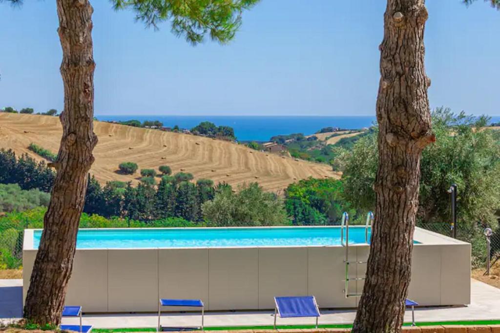 - une piscine avec 2 palmiers et des chaises dans l'établissement Villa degli Archi by Mmega, à SantʼElpidio a Mare