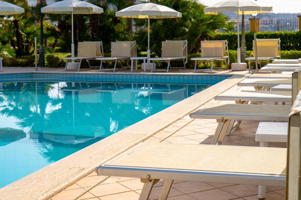 une piscine avec chaises longues et parasols dans l'établissement Hotel Villa Romana, à Porto Empedocle