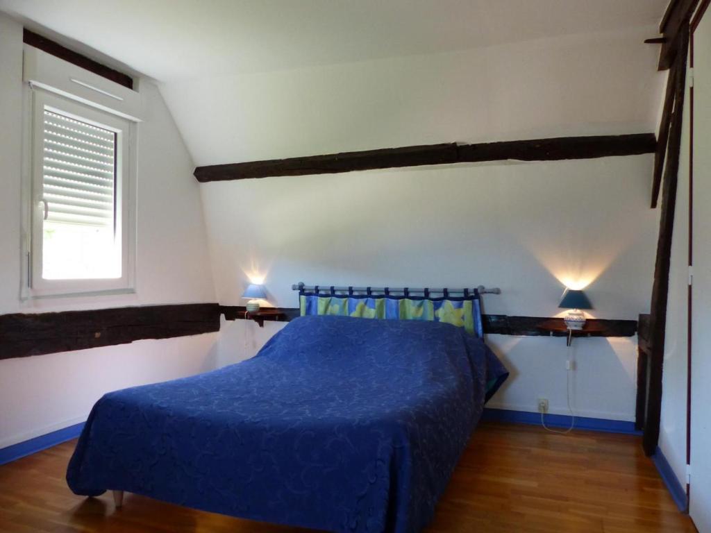 - une chambre avec un lit bleu avec des draps bleus et une fenêtre dans l'établissement Maison solognote avec piscine chauffée, jardin et équipements complets près du Pal. - FR-1-489-12, à Diou