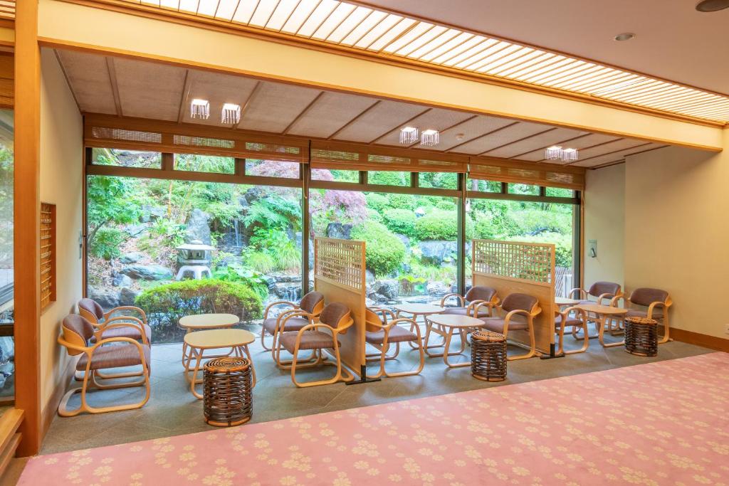 une pièce avec des tables et des chaises et une grande fenêtre dans l'établissement Shikitei Morioka TsunagiOnsen, à Morioka