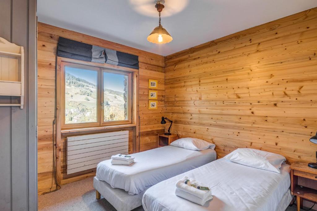Ce lit se trouve dans un dortoir doté de murs en bois et d'une fenêtre. dans l'établissement Appartement Stenoga - Welkeys, à Megève