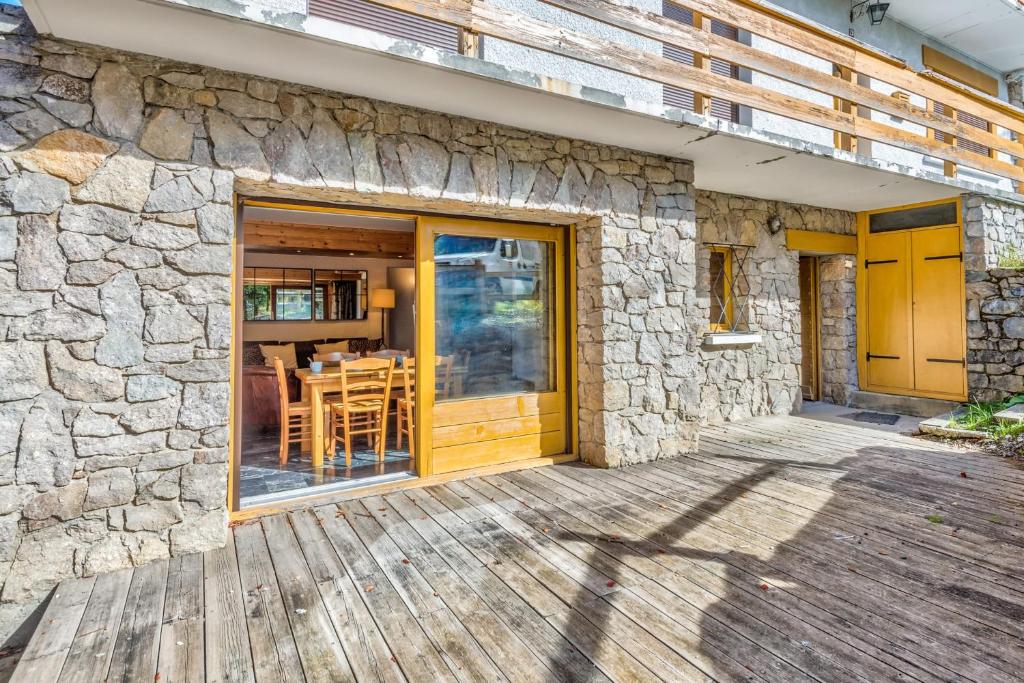 une maison en pierre avec une porte en bois et une terrasse en bois dans l'établissement Appartement Stenoga - Welkeys, à Megève