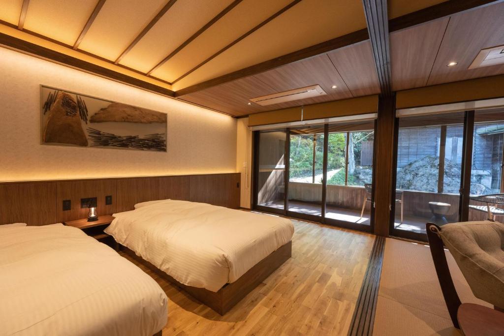 une chambre avec deux lits et une grande fenêtre dans l'établissement Rankeisou, à Sanjo