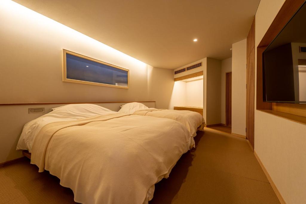 une chambre avec un lit blanc et une télévision à écran plat dans l'établissement Monjusou Shourotei, à Miyazu