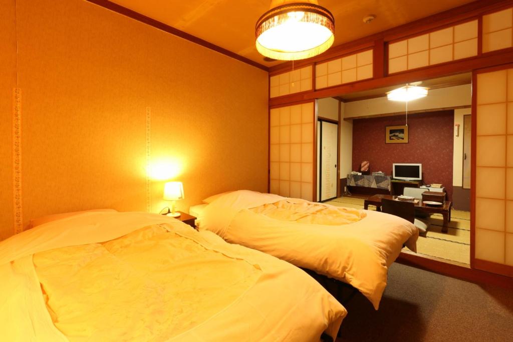 une chambre avec deux lits et un salon avec un bureau dans l'établissement Dai Onsen Matsudaya Ryokan, à Hanamaki 36 autres photos