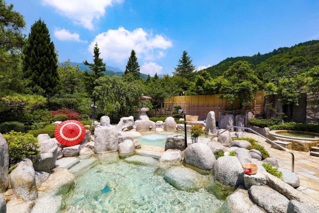 une piscine dans un jardin avec des rochers et des arbres dans l'établissement TAOYA Kisoji, à Nagiso