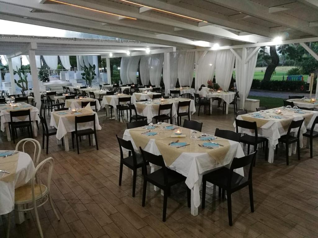 un restaurant avec tables et chaises et nappes blanches dans l'établissement Resort Sciabache, à Zambrone