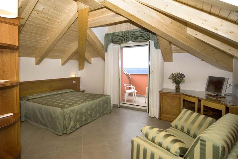 une chambre avec un lit, un canapé et une fenêtre dans l'établissement Hotel Lido, à Deiva Marina