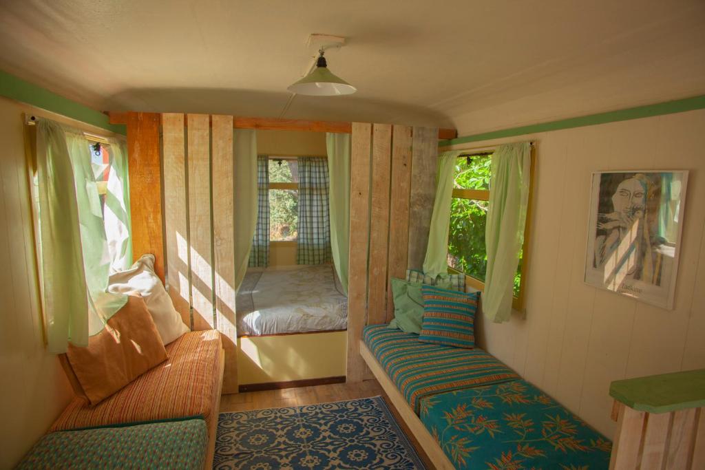 Cette petite chambre dispose d'un canapé, d'un lit et de fenêtres. dans l'établissement le bon chemin roulotte, à Fage