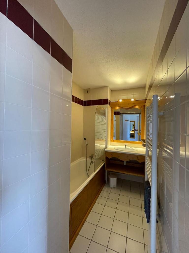 une salle de bain avec une baignoire, un lavabo et un miroir dans l'établissement LA TANIA COURCHEVEL 73120, à Courchevel