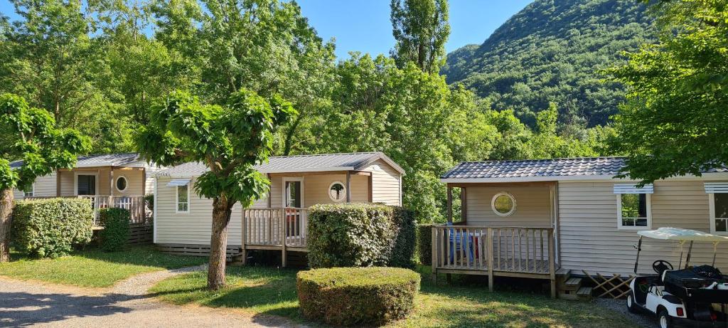 Une rangée de mobile homes avec des arbres et une montagne dans l'établissement Camping Le Gallo Romain, à Barbières