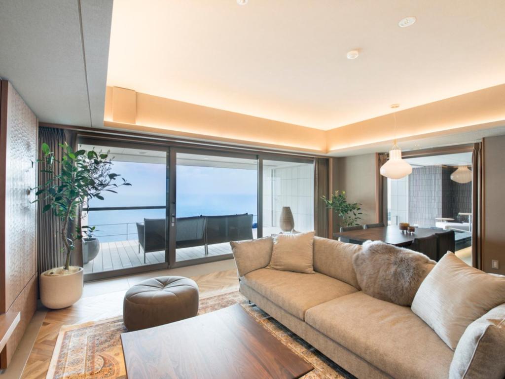 un salon avec un canapé et une vue sur l'océan dans l'établissement Atami Sekaie, à Atami