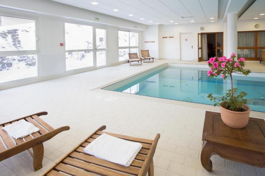- une piscine avec 2 chaises, une table et une table dans l'établissement Espace et confort de 45 m2 dans station familiale à 1800, à Puy-Saint-Vincent