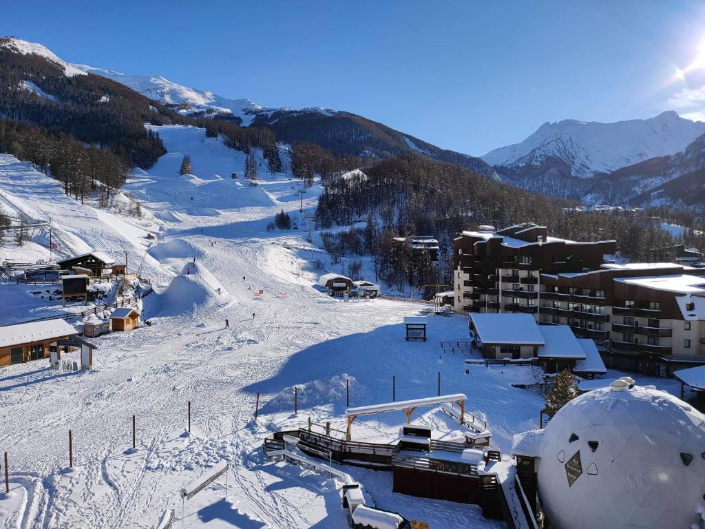 une montagne enneigée avec une piste de ski avec des bâtiments dans l'établissement Cocon d'altitude - Studio avec vue sur les pistes, aux Orres