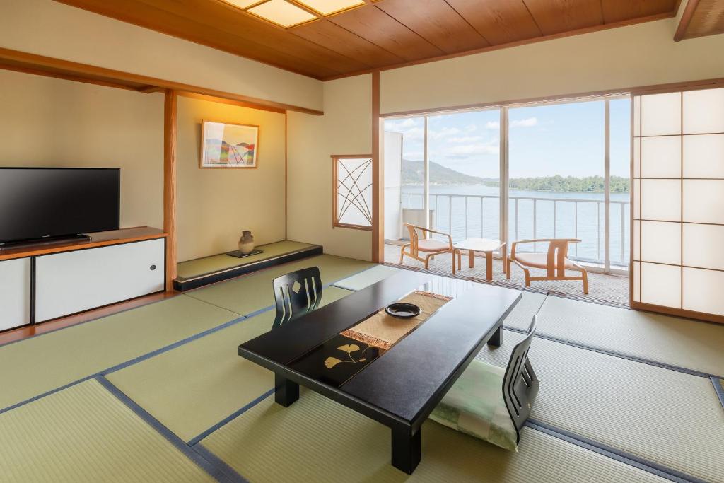 un salon avec une télévision, une table et des chaises dans l'établissement Amano Hashidate Hotel, à Miyazu