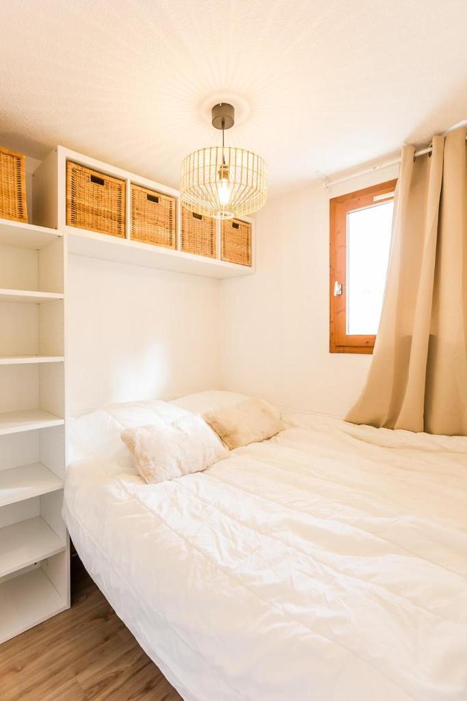 une chambre avec un grand lit blanc et une fenêtre dans l'établissement Appartement Les Arcs Ski aux pieds à Vallandry, à Landry
