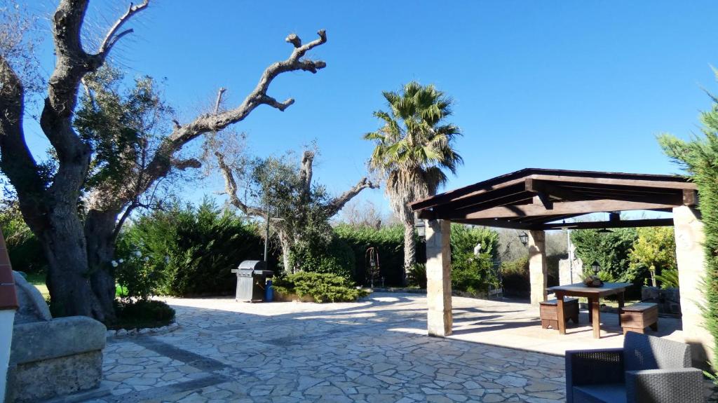 une terrasse en pierre avec un abri en bois et des palmiers dans l'établissement Villa Piana - Con Piscina e Giardino privato nel Salento, à Tricase