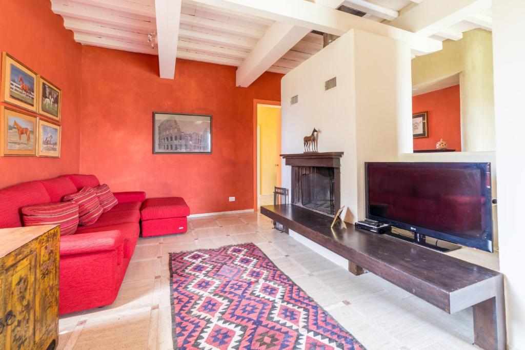 un salon avec un canapé rouge et une cheminée dans l'établissement Villa Fragranza - Homelike Villas, à Buonconvento