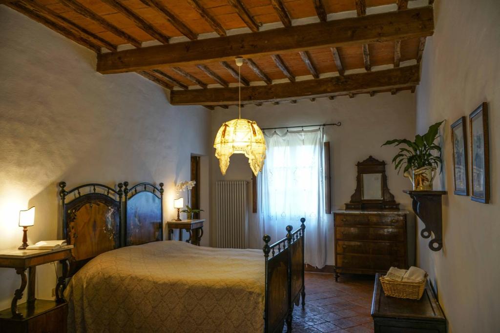 une chambre avec un grand lit et un lustre dans l'établissement Borgo La Pievina - Pool Villa, à Palazzina