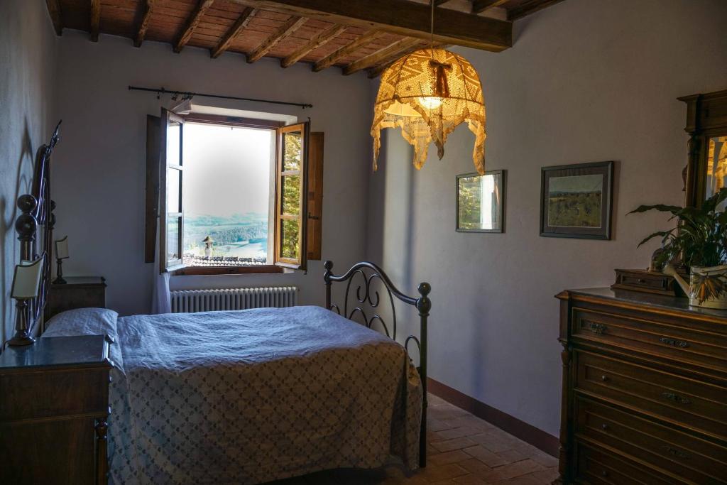 une chambre avec un lit, une fenêtre et un lustre dans l'établissement Borgo La Pievina - Pool Villa, à Palazzina