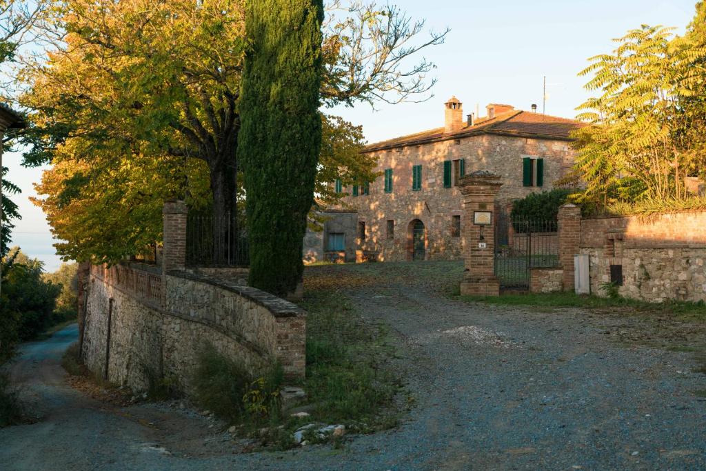une vieille maison en pierre avec un arbre en face de celle-ci dans l'établissement Borgo La Pievina - Pool Villa, à Palazzina