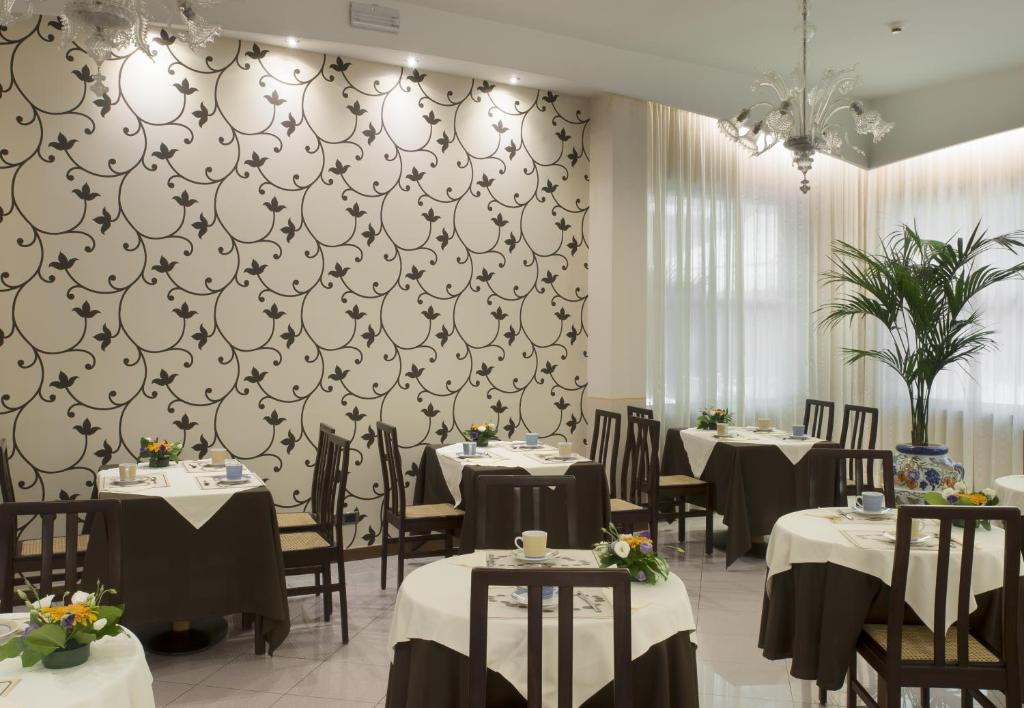 une salle à manger avec des tables, des chaises et un mur dans l'établissement ACasaMia WelcHome Hotel, à Rimini