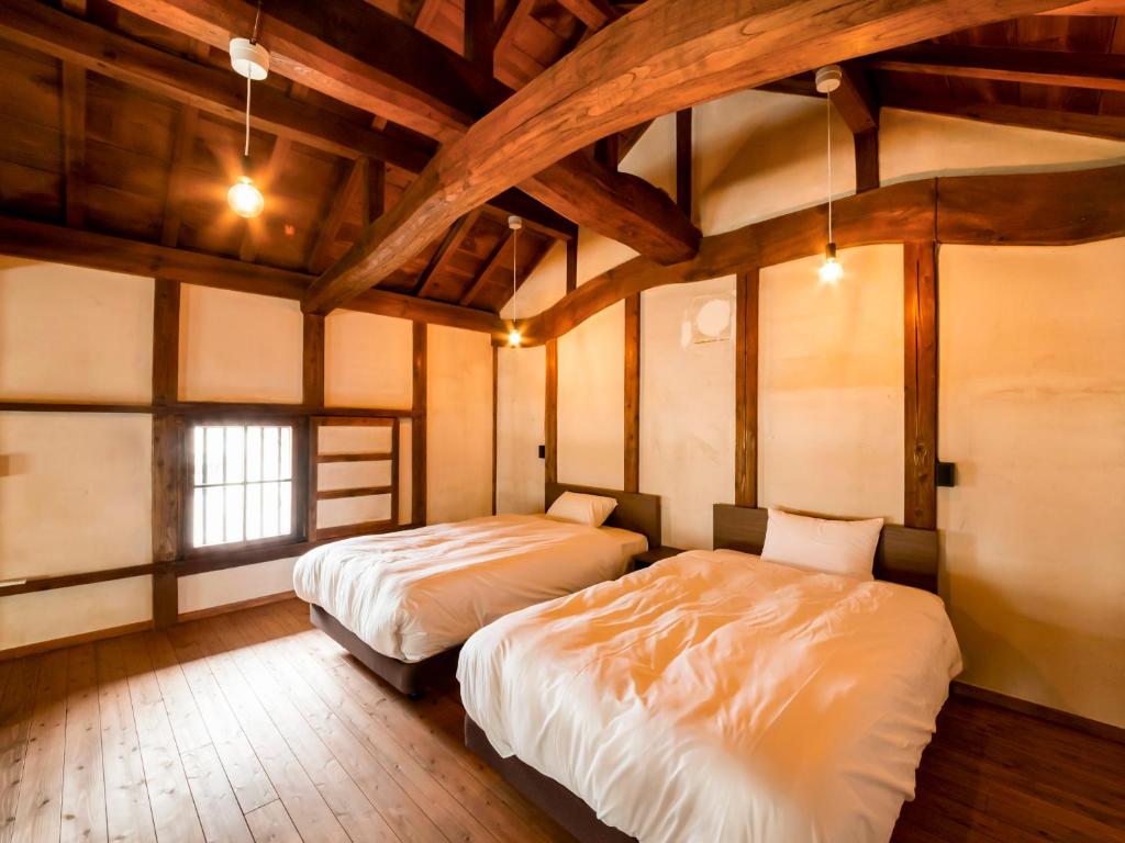 deux lits dans une chambre avec plafonds en bois dans l'établissement NIPPONIA Chichibu Monzenmachi, à Chichibu