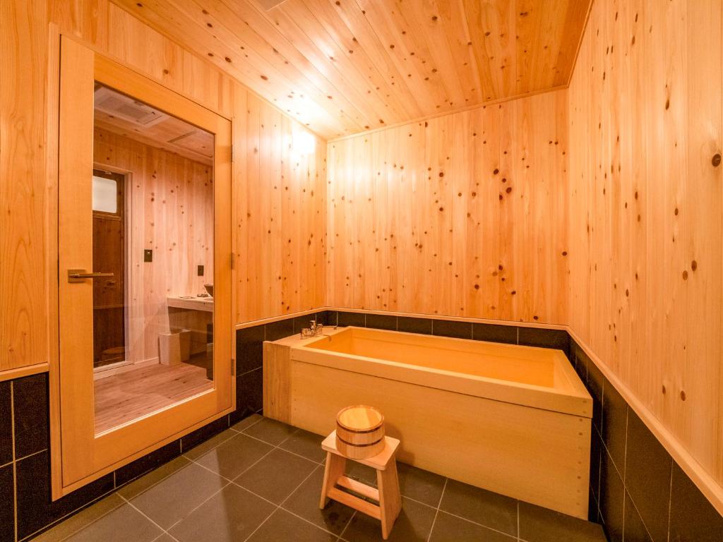 La salle de bains en bois est pourvue d'une baignoire et d'une douche. dans l'établissement NIPPONIA Chichibu Monzenmachi, à Chichibu