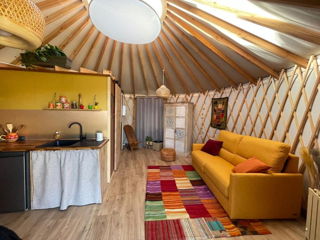 - un salon avec un canapé jaune dans une yourte dans l'établissement Yourte ,volcans,randonnées,lacs,quiétude, à Grandeyrolles