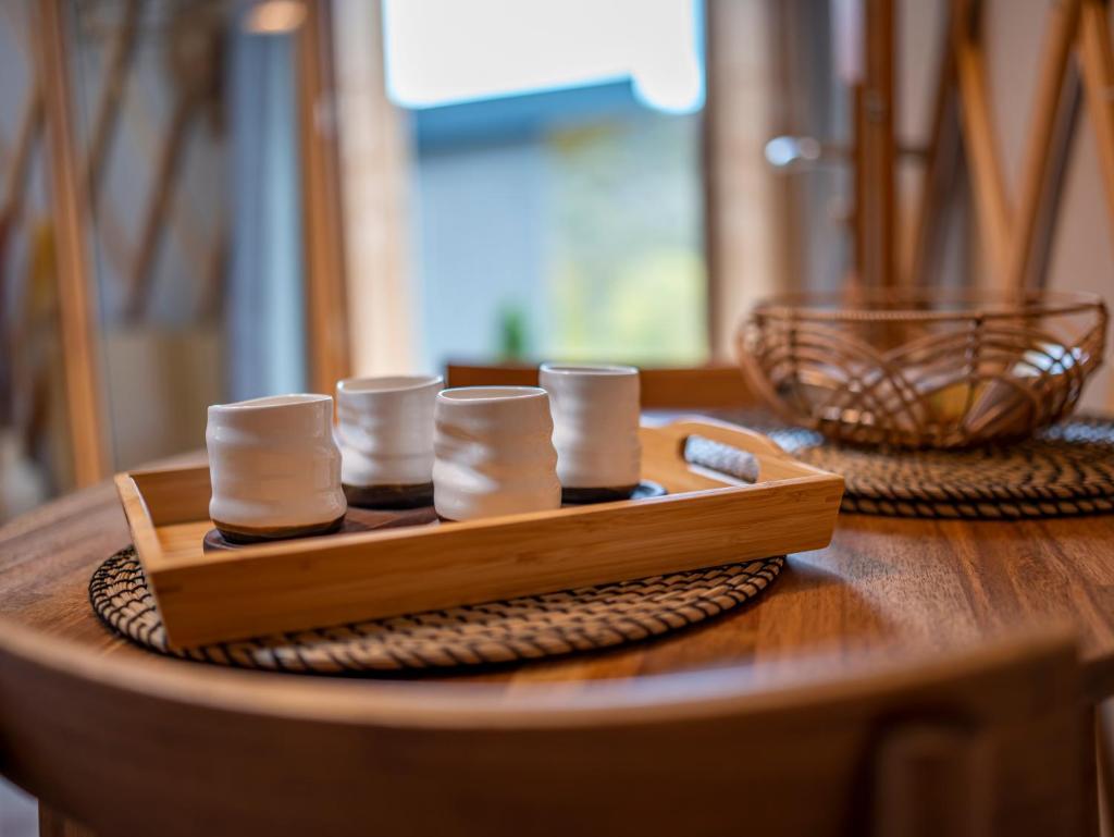 - un plateau en bois avec quatre tasses sur une table dans l'établissement Yourte ,volcans,randonnées,lacs,quiétude, à Grandeyrolles 16 autres photos