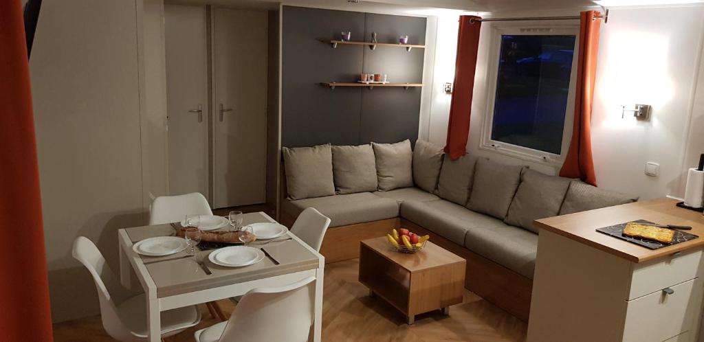 un petit salon avec un canapé et une table dans l'établissement MOBIL HOME CLIMATISE TOUT CONFORT 6 à 8 PERSONNES à louer, à Litteau